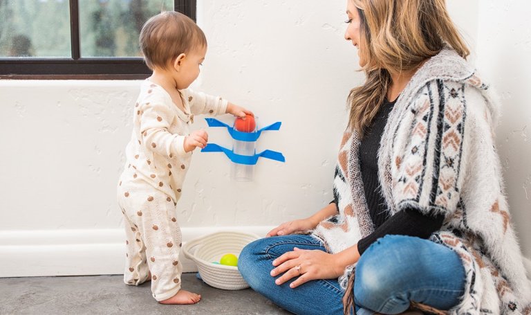 Baby playing with balls in a clear tube