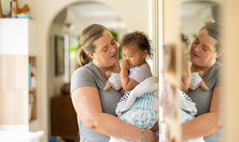 Baby sucking their thumb while holding a Cotton Doll by Lovevery