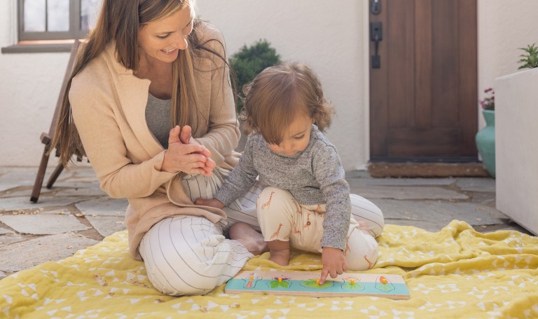 Toddler playing with the Community Garden Puzzle by Lovevery