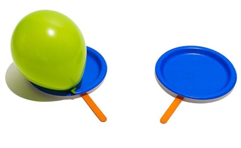 Green balloon on a blue paper plate with a wooden stick attached