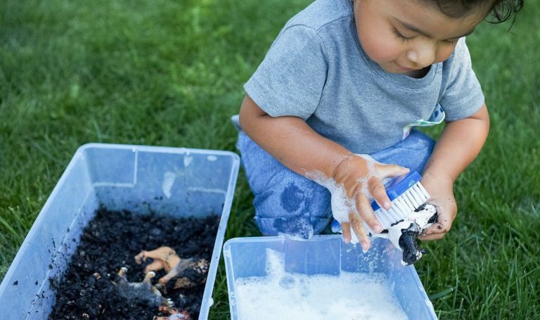 Toddler playing outside and washing an animal figurine that was in dirt