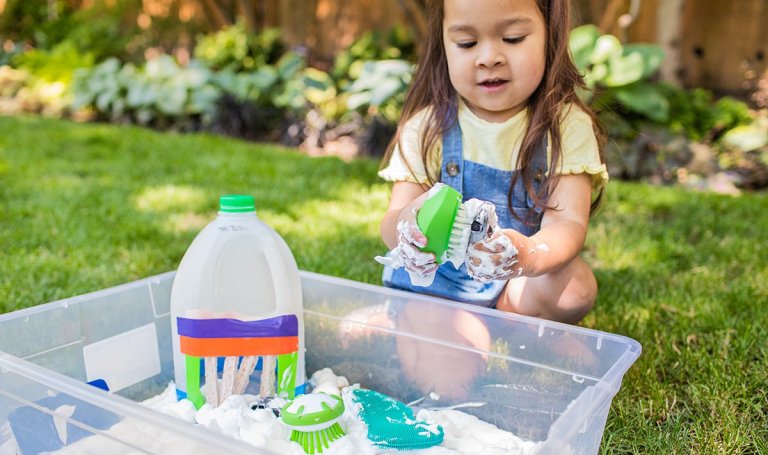 Child plays with suds in a water table.