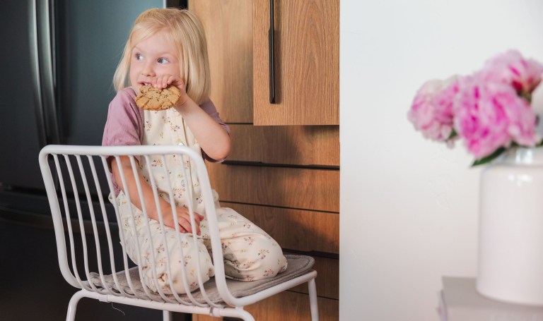 Toddler sitting on a chair eating a cookie