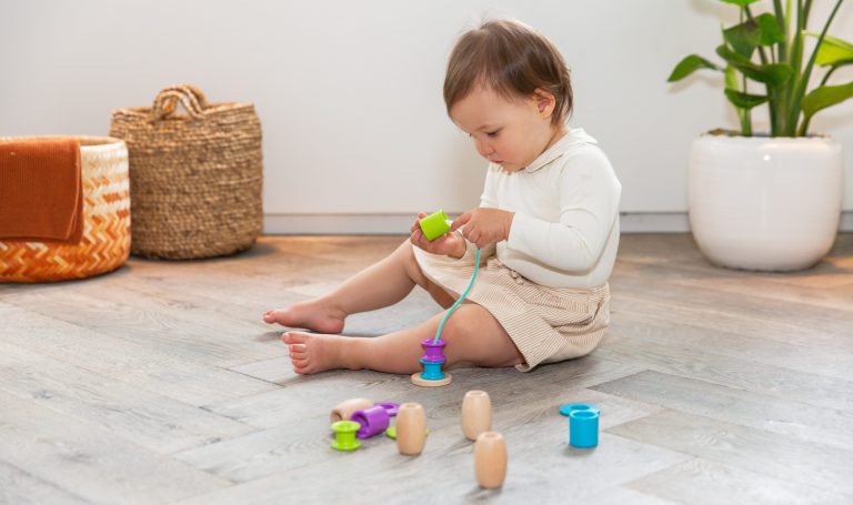 Toddler playing with the Threadable Bead Kit by Lovevery