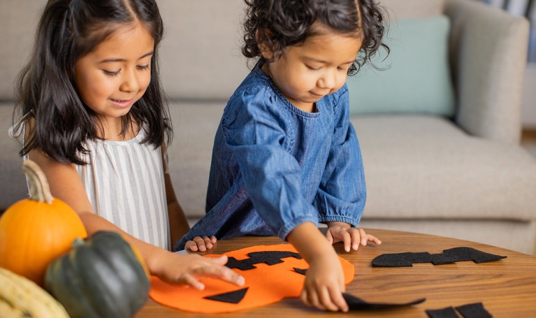 Two children making a felt pumpkin