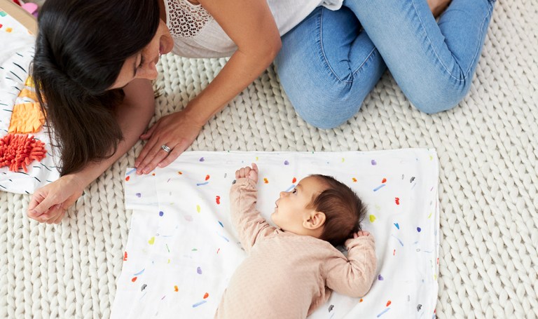 Baby laying on the ground with their mom