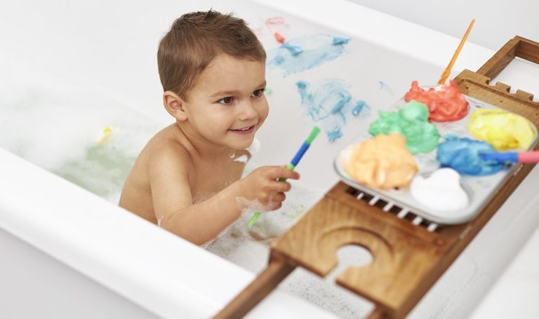 Child playing with color foam in the bathtub