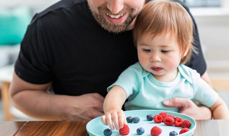 Father and daughter sort berries on a plate.