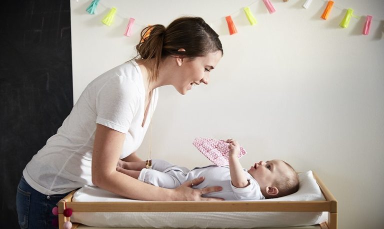 Woman looking down on a baby laying on a changing table
