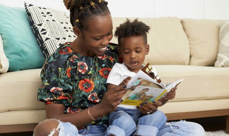 Toddler sitting on a woman's lap looking at a book