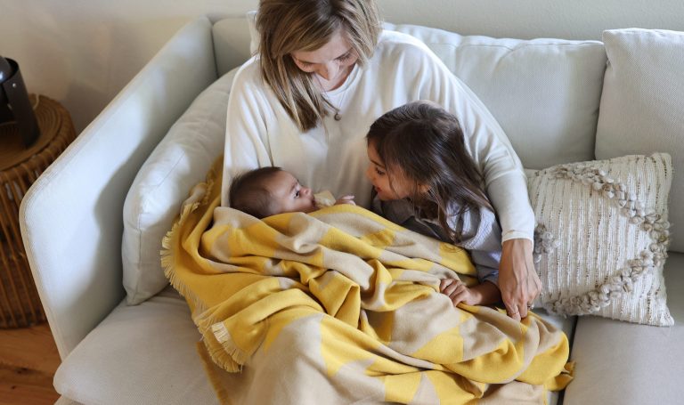 Mother cuddling a baby and toddler