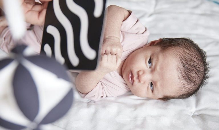 Baby laying on its side looking at high contrast Black and White cards by Lovevery